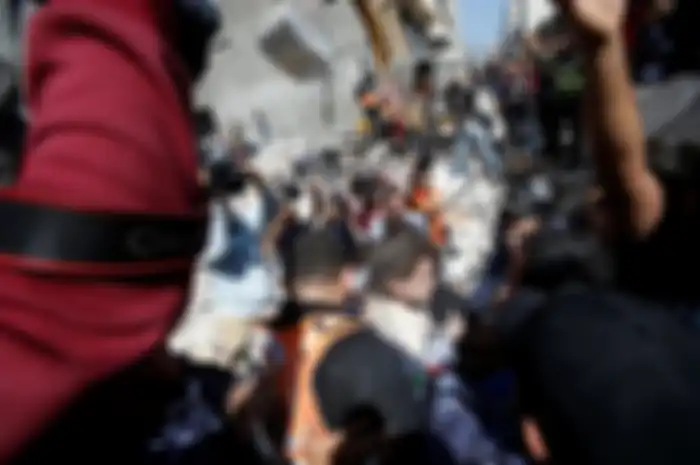 Warga Palestina mengevakuasi gadis cilik dari puing-puing rumah yang hancur setelah serangan udara Israel di Kota Gaza pada 16 Mei 2021.