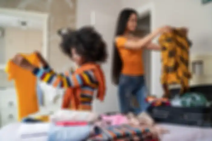 Girls packing clothes in suitcase for travel