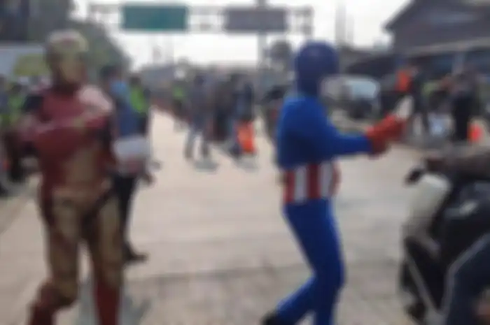 Polisi libatkan maskot Ironman dan pahlawan super di kegiatan bagi-bagi makanan di pos penyekatan Sasak Jarang Bekasi, Jumat (16/7/2021). 