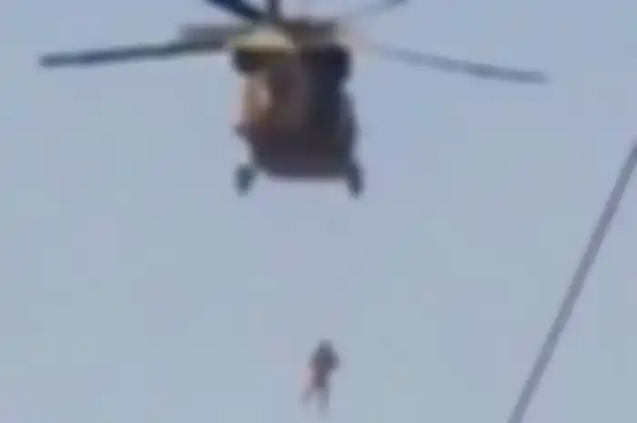 Seseorang yang terlihat digantung di bawah helikopter Black Hawk yang sedang dioperasikan oleh Taliban.