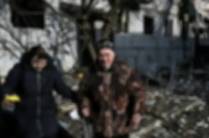 Potret warga Ukraina di depan pemukinan yang rusak akibat serangan Rusia.