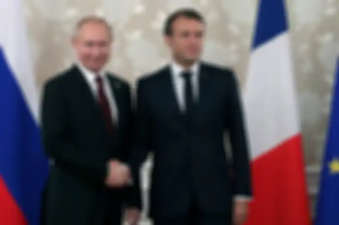 Presiden Rusia Vladimir Putin dan Emmanuel Macron berjabat tangan di pertemuan G20 pada 2019.