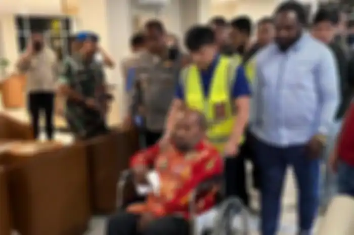 Gubernur Papua Lukas Enembe harus menggunakan kursi roda saat hendak masuk pesawat sebelum bertolak ke Jakarta dari Bandara Internasional Sam Ratulangi Manado, Selasa (10/01/2023) malam. 