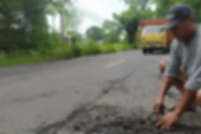 Gufron saat memperbaiki ruas Jalan Raya Kecamatan Deket-Karangbinangun, Lamongan, Jawa Timur, Rabu (1/2/2023).