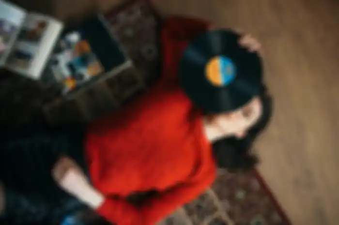 Young woman enjoying at home listening to vinyl records from above.