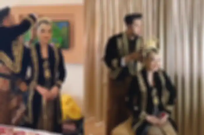 Calon pengantin pria terlihat telaten memasang aksesoris adat di kepala pengantin. 