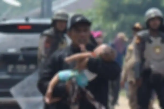 Herman menggendong bayinya yang pingsan di tengah bentrokan warga Rempang dan aparat gabungan di Jembatan 4 Barelang, Batam, Kamis (7/9/2023). Bayinya pingsan karena gas air mata masuk ke dalam rumahnya lewah jendela yang terbuka. 