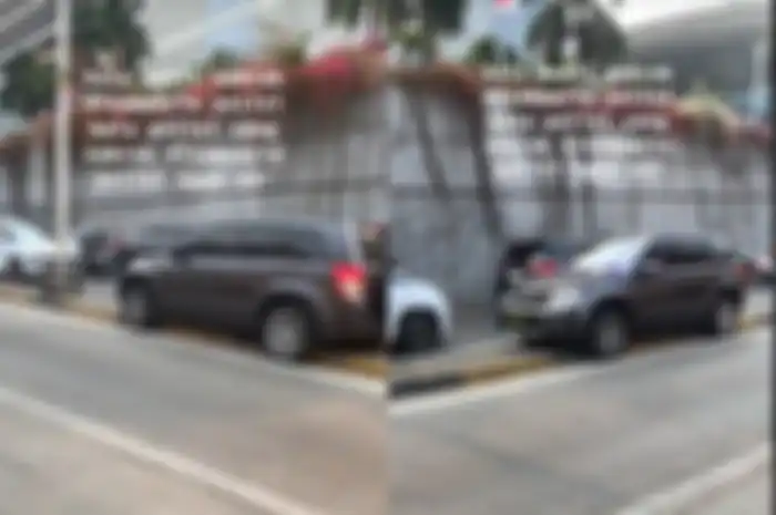 Sebuah mobil dinas polisi menabrak tiang lampu dan terjebak di pembatas jalan.