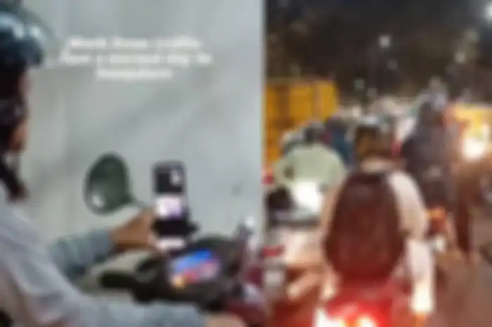 wanita melakukan rapat online sambil mengendarai motor saat terjebak macet 