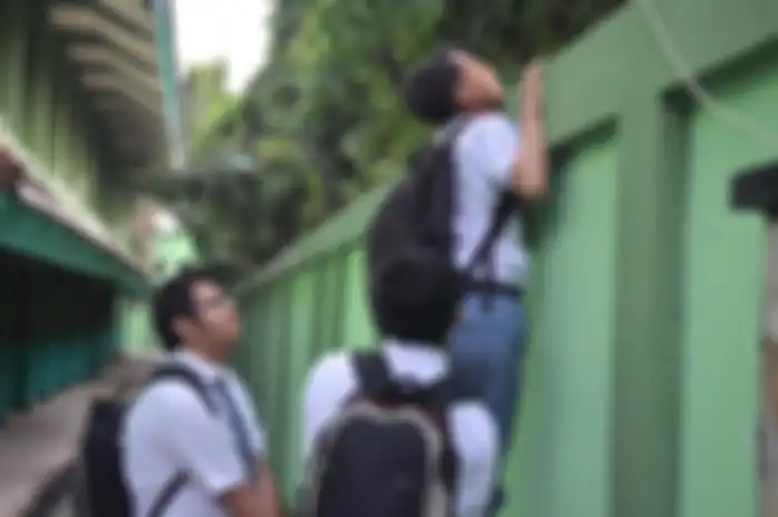 (foto ilustrasi) pelajar SMA memanjat tembok sekolah demi bolos
