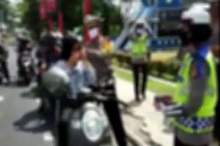 Razia polisi sambil membagikan masker ke pengendara motor.