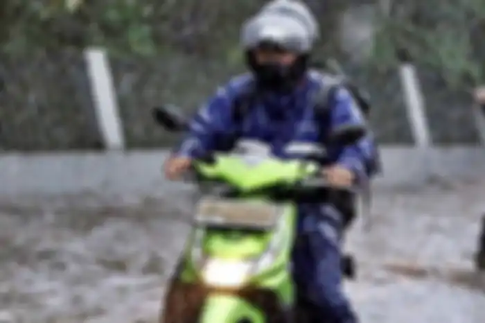 Ilustrasi pemotor berkendara saat hujan lebat.