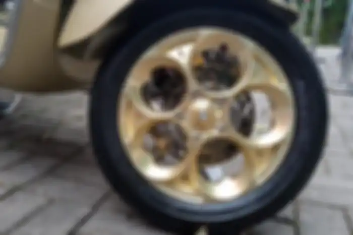 Tersemat pelek Maru's W252 gold dibalut ban Mitas di modifikasi motor Vespa Primavera 75th Anniversary.
