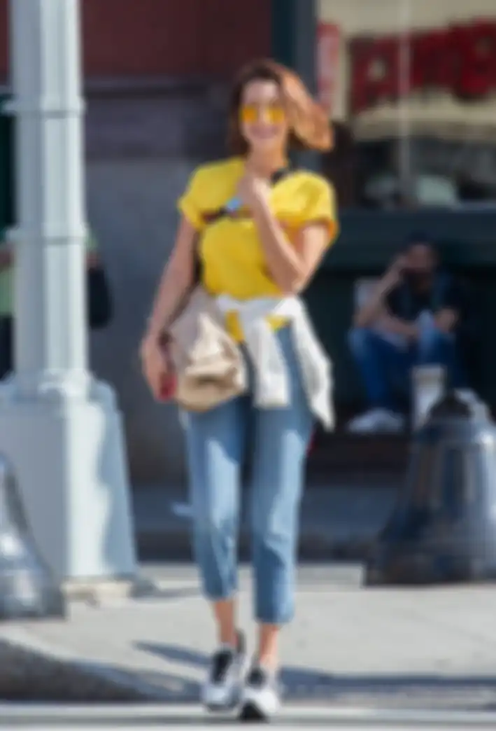 Bella Hadid memakai kaos kuning dan cropped jeans