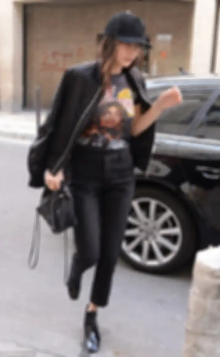 Bella Hadid memakai printed tee, jeans, dan bomber jacket