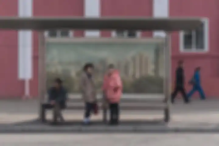 Halte bus di Pyongyang menampilkan lanskap kota di latar belakangnya.