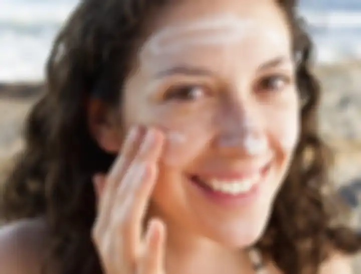 Smiling woman applying sunscreen to face