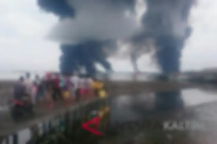 Sejumlah warga menyaksikan kobaran api dan asap hitam di perairan laut Teluk Balikpapan pada Sabtu (31/3/2018
