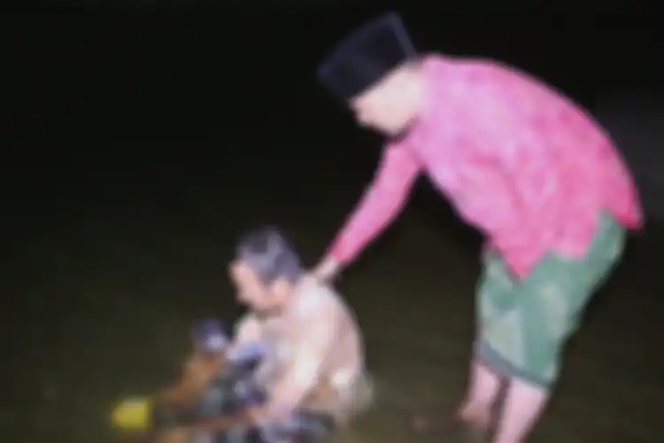 Ustaz Ujang Bushtomi pemilik Padepokan Anti Galau memandikan Mursyid (45) di Waduk Setupatok, Selasa malam (24/4/2019).