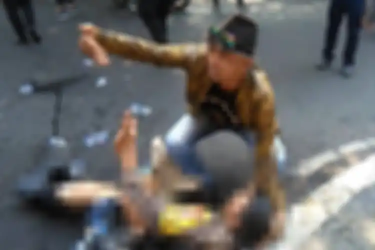 Seseorang coba memberikan pertolongan kepada seorang anggota polisi yang terbakar saat terjadi insiden kericuhan dalam aksi unjukrasa.