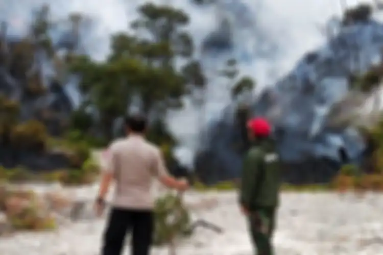 Tampak pepohonan dan ilalang di daerah wisata Kawah putih terbakar dan memunculkan asap pekat yang mengitarinya.