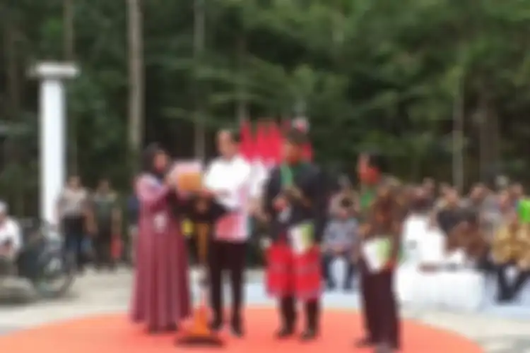 Presiden Jokowi menunjukkan SK Perhutanan Sosial kepada seorang ibu yang curhat soal lahan kebun sawitnya di eksekusi di Desa Gondai, Kabupaten Pelalawan, saat menyerahkan SK Perhutanan Sosial di Tahura Sultan Syarif Kasim, Kecamatan Minas, Kabupaten Siak, Riau, Jumat (21/2/2020).