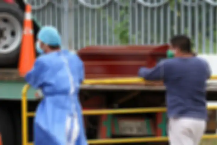  Seorang pria dengan masker wajah (kanan) menunggu jenazah kerabatnya, di sebelah seorang petugas di luar sebuah rumah sakit di Guayaquil, Ekuador, Rabu (1/4/2020). Otoritas Ekuador dalam beberapa hari terakhir telah mengumpulkan setidaknya 150 jenazah dari jalan-jalan dan rumah para warga di Kota G