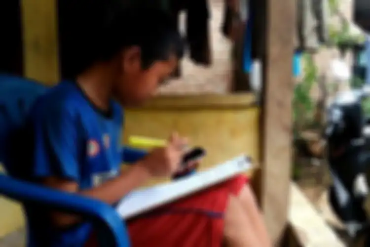 Jonathan (13) pelajar SMP di Bandar Lampung sedang memahami soal dari pembelajaran daring kelasnya, Kamis (6/8/2020). Untuk memenuhi kebutuhan kuota internet, Jonathan berjualan pempek di sekitar kampung.