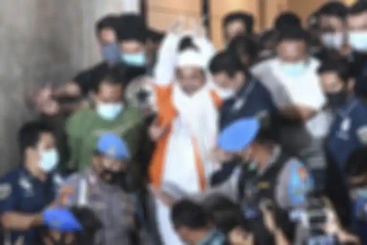 Imam Besar Front Pembela Islam (FPI) Habib Rizieq Shihab (tengah) berjalan menuju mobil tahanan usai diperiksa di Mapolda Metro Jaya, Jakarta, Minggu (13/12/2020) dini hari. Rizieq Shihab ditahan penyidik Ditreskrimum Polda Metro Jaya untuk kepentingan penyidikan perkara kasus dugaan pelanggaran pro