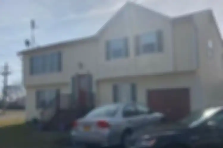 Rumah Long Island terlihat relatif rapi dari luar, tetapi tidak dalam kondisi bagus di dalam dengan Mercedes model terbaru terparkir di depan rumah bersama dengan mobil Volkswagen.