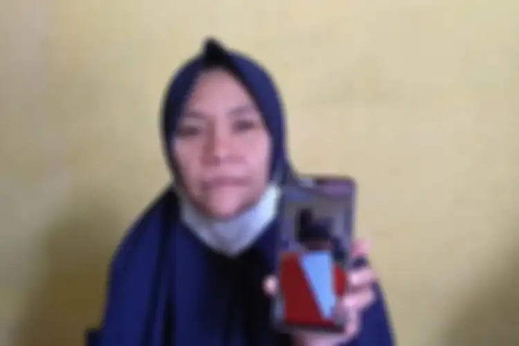 Lia Pratiwi (42) menunjukkan foto anaknya, M. Reza Aulia (10) membawa berkas laporan di Polsek Tuntungan pada Jumat (11/6/2021).