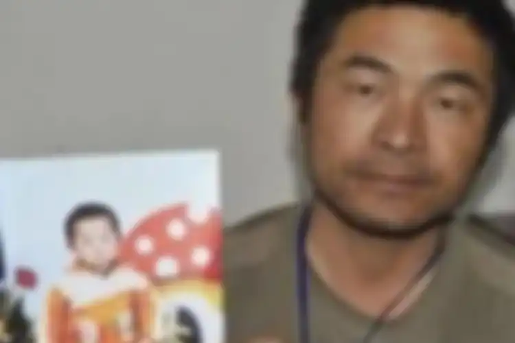 Guo Gangtang sedang memegang foto putranya pada 24 tahun silam yang diculik
