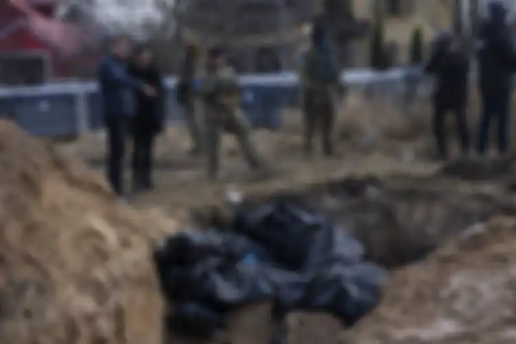 Tentara Ukraina berdiri di samping kuburan massal di Bucha, pinggiran Kyiv