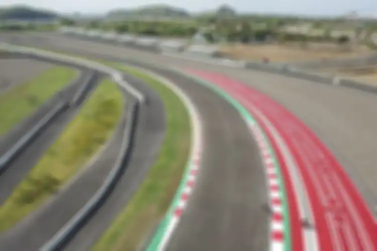 Circuit Mandalika dengan kerbs merah-putih, hijau untuk track limit, dan area run safe bermotif khas corak lombok. 