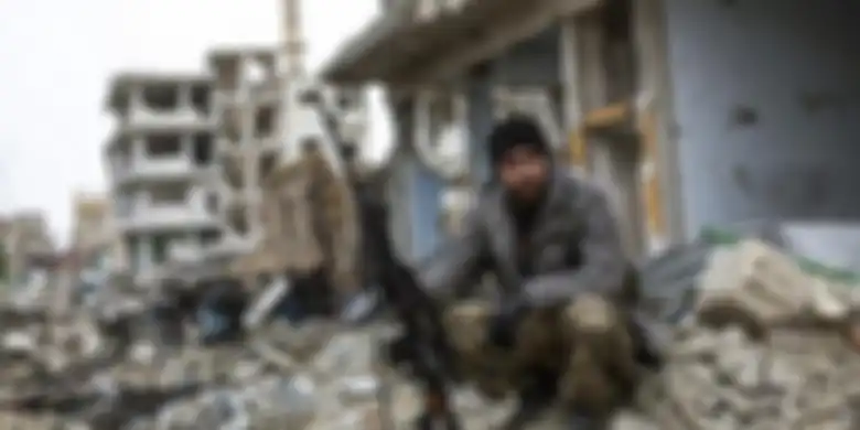 Seorang penembak jitu Kurdi Suriah duduk di antara puing-puing di kota Kobani, Suriah
