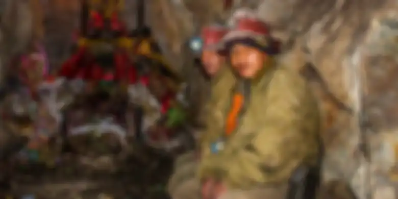 Pekerja Tambang Cerro Rico, Bolivia dan Patung El Tio di belakangnya.