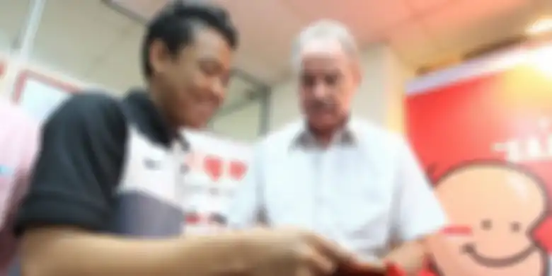 Pelatih timnas Indonesia, Alfred Riedl (kanan), saat melayani permintaan tanda tangan dari salah sat
