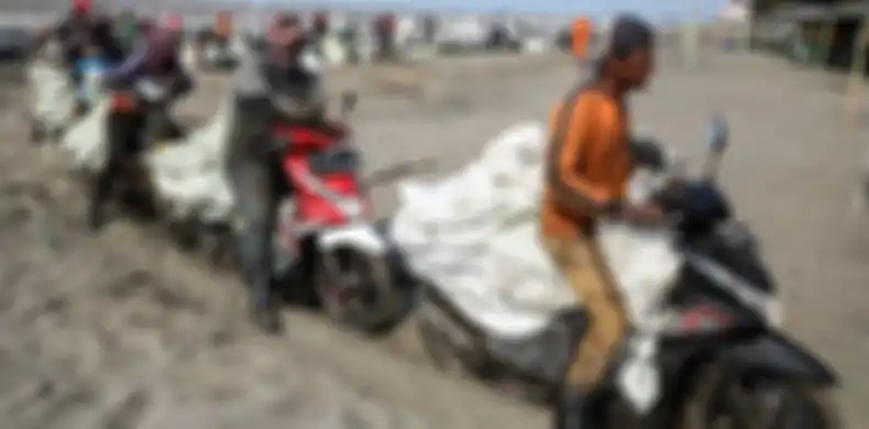 Warga menggunakan motor untuk mengangkut karung yang berisi tumpahan minyak Oil Spill yang tercecer milik Pertamina di Pesisir Pantai Cemarajaya, Karawang, Jawa Barat, Minggu (4/8/2019). Pasir yang tercemar minyak tersebut dikumpulkan dan akan dipindahkan ke pabrik penyimpanan limbah B3 (Bahan Berbahaya dan Beracun) untuk dimusnahkan.