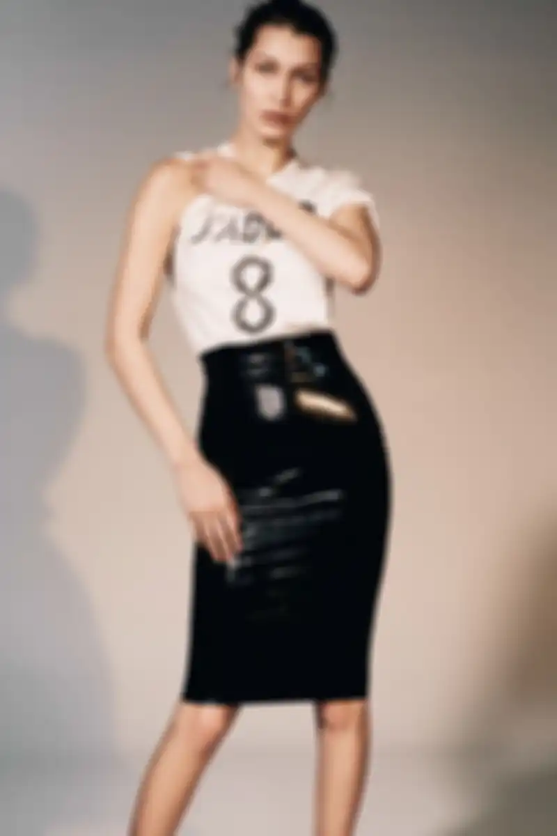 Bella Hadid memakai kaos putih dan vinyl skirt