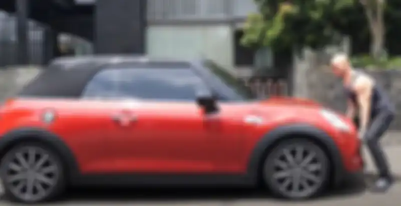 Aksi Deddy Corbuzier saat mencoba mengangkat Mini Cooper dengan tangan kosong