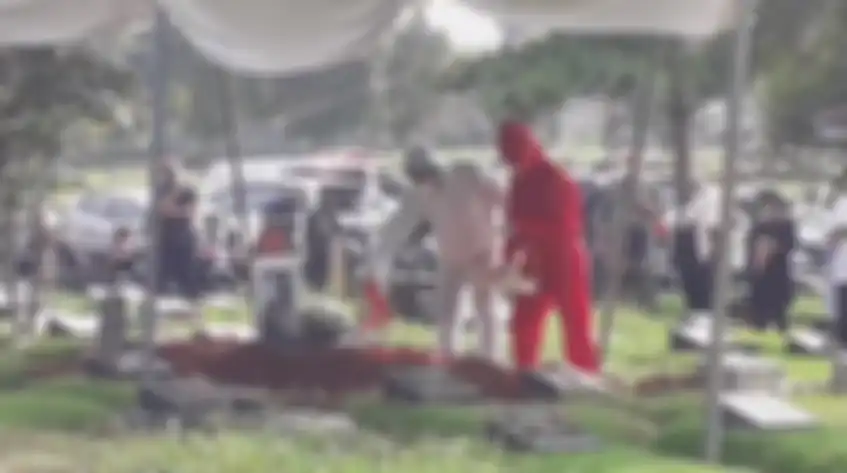 Teddy Syah dan anaknya menaburkan bunga di pusara Rina Gunawan. 