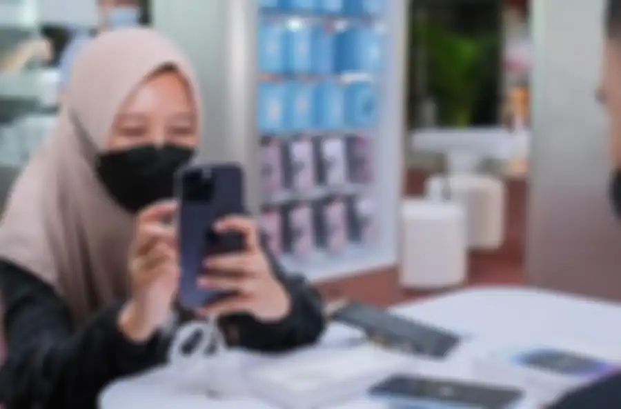 Calon pembeli sedang mencoba langsung iPhone 14 di iBox