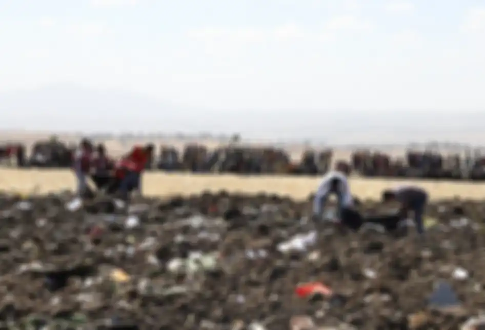 Petugas mengevakuasi jenazah di lokasi jatuhnya pesawat Ethiopia Airlines di kawasan Bishoftu, sebuah kota sekitar 60 kilometer tenggara Addis Ababa, Ethiopia, Minggu (10/3/2019). Sebanyak 157 orang terdiri dari penumpang dan kru pesawat Ethiopian Airlines dipastikan tewas setelah Boeing 737-8 MAX y