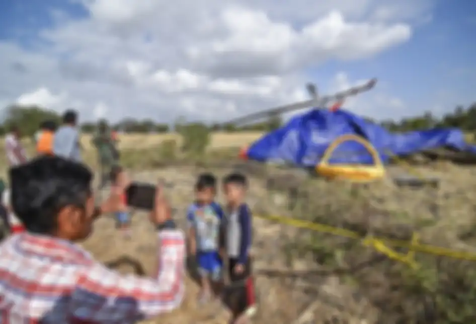 Seorang laki-laki memotret anaknya dengan latar belakang pesawat helikopter yang jatuh di Dusun Gilik, Desa Kawo, Kecamatan Pujut, Lombok Tengah, NTB, Senin (15/7/2019). Persawahan kering yang merupakan lokasi jatuhnya pesawat helikopter B206L4 PKCDV ramai dikunjungi warga yang ingin mengabadikan pe