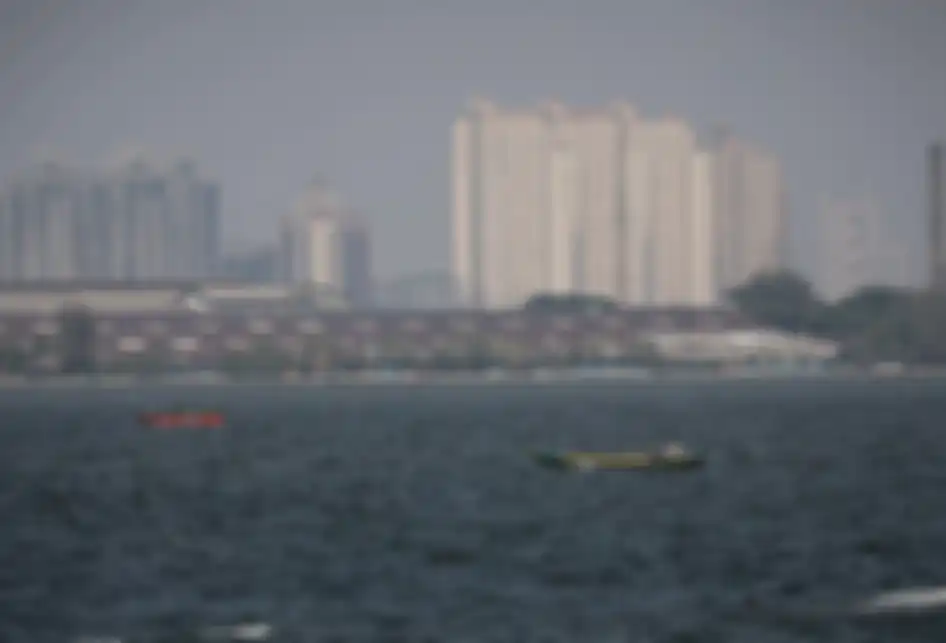 Pemandangan laut dengan latar belakang gedung bertingkat yang diselimuti asap polusi di Jakarta Utara, Rabu (31/7/2019). Berdasarkan data situs penyedia peta polusi daring harian kota-kota besar di dunia AirVisual, menempatkan Jakarta pada urutan pertama kota terpolusi sedunia pada Senin (29/7) pagi