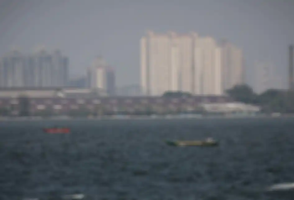 Pemandangan laut dengan latar belakang gedung bertingkat yang diselimuti asap polusi di Jakarta Utara, Rabu (31/7/2019). Berdasarkan data situs penyedia peta polusi daring harian kota-kota besar di dunia AirVisual, menempatkan Jakarta pada urutan pertama kota terpolusi sedunia pada Senin (29/7) pagi