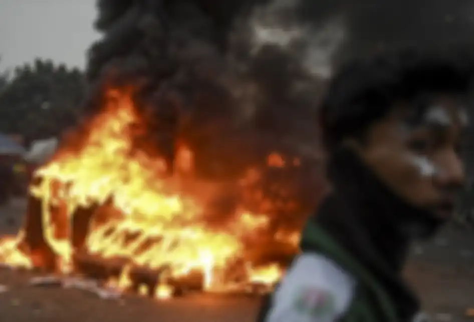 Mahasiswa melintas di dekat pembatas jalan yang dibakar saat aksi menolak UU KPK yang berakhir ricuh di kawasan Senayan, Jakarta, Selasa (24/9/2019). Demo mahasiswa yang berlangsung di depan Gedung DPR sejak tadi pagi berakhir ricuh, suasana tidak kondusif terjadi sejak sore hingga malam hari.