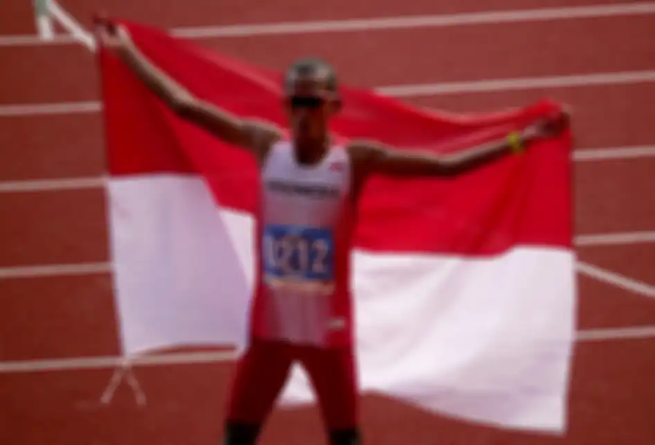 Pelari Indonesia Agus Prayogo mengibarkan bendera Merah Putih seusai memasuki garis finish nomor marathon putra SEA Games 2019 di Stadion Atletik New Clark City, Clark, Filipina, Jumat (6/12/2019). Agus berhasil menyumbangkan medali emas pertama cabang atletik setelah menyelesaikan lomba sepanjang 4
