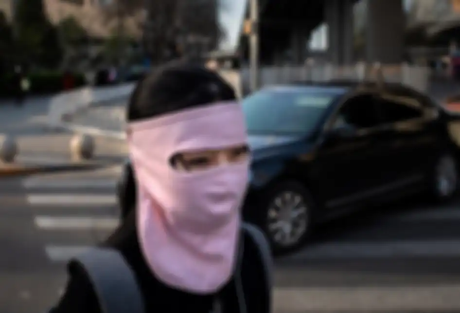 Seorang wanita mengenakan masker kain yang menutupi hampir seluruh wajahnya di tengah wabah virus corona (Covid-19) saat berjalan di luar gedung perkantoran di Beijing, China, Rabu (1/4/2020).