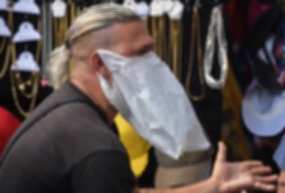 Seorang pedagang kaki lima memakai tas plastik sebagai pengganti masker dalam upaya mencegah penularan virus corona (Covid-19), di pusat kota Sao Paulo, Brasil, Senin (16/3/2020).